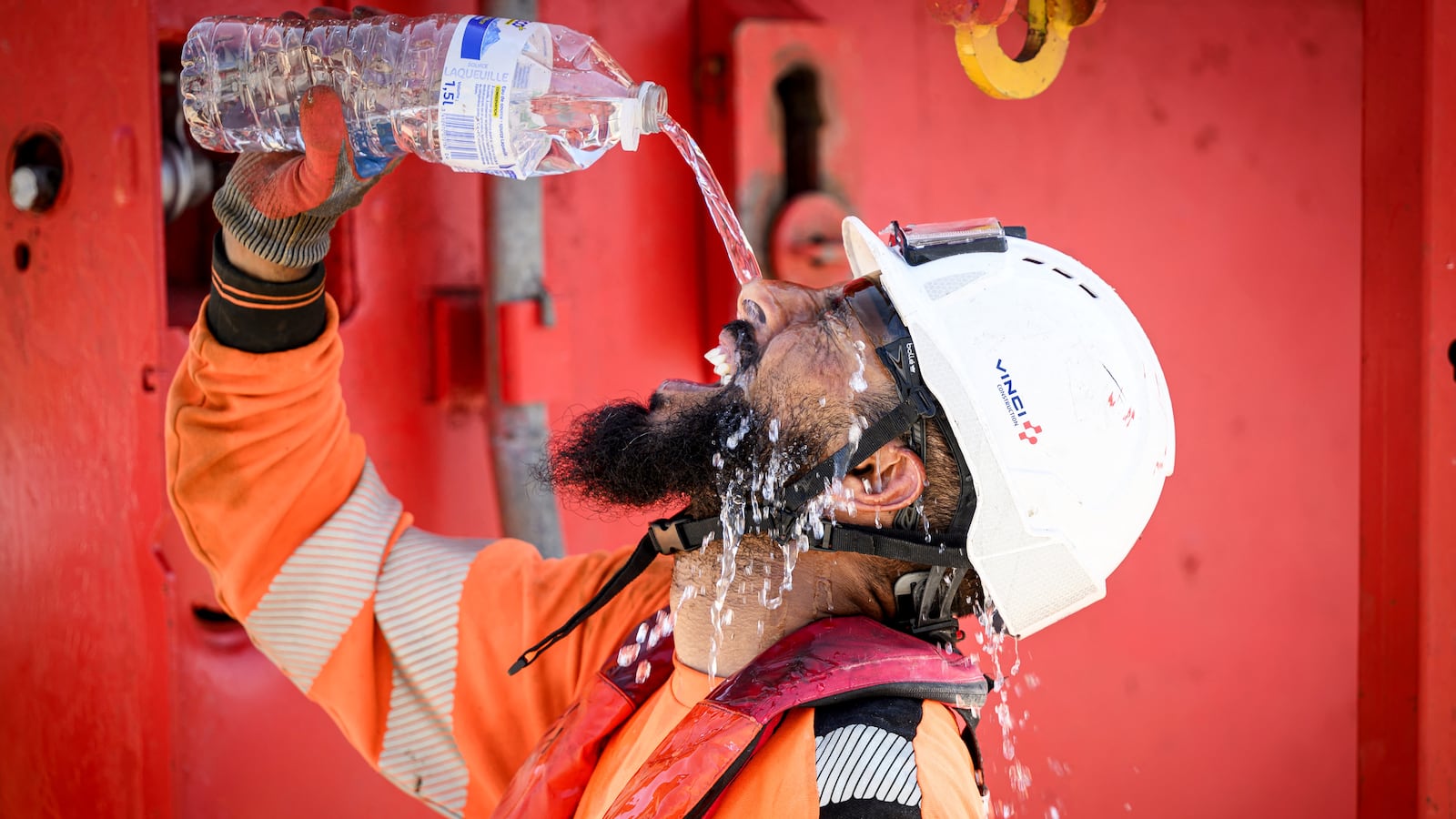 Construction worker cools off with a bottle of water.