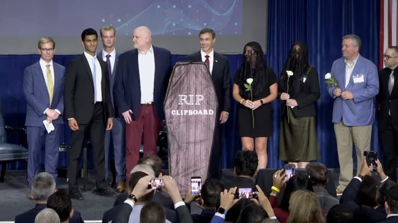 A group of DHHS employees holds up a cardboard coffin labeled "RIP Clipboard"