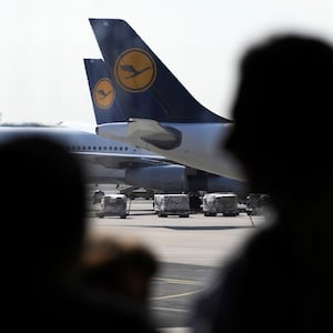 Passengers are silhouetted near airplanes of German airline Lufthansa that are parked at Frankfurt airport July 31, 2008. Germany's Deutsche Lufthansa will scrap about 10 percent of its flights to German and European destinations in the next five days in response to a strike by ground and cabin staff over pay, it said on Wednesday. REUTERS/Kai Pfaffenbach (GERMANY)