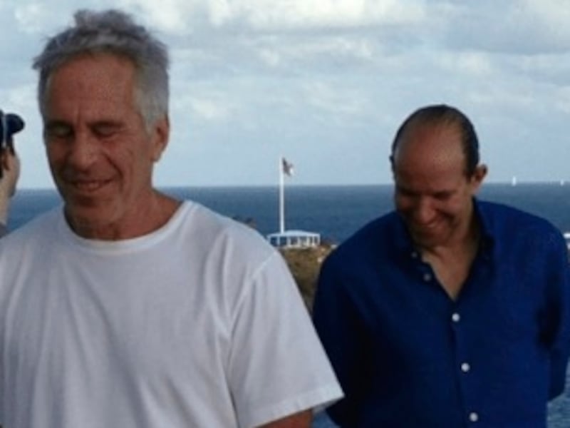 Jeffrey Epstein in white photographed on his island against the background of the sea with three other men