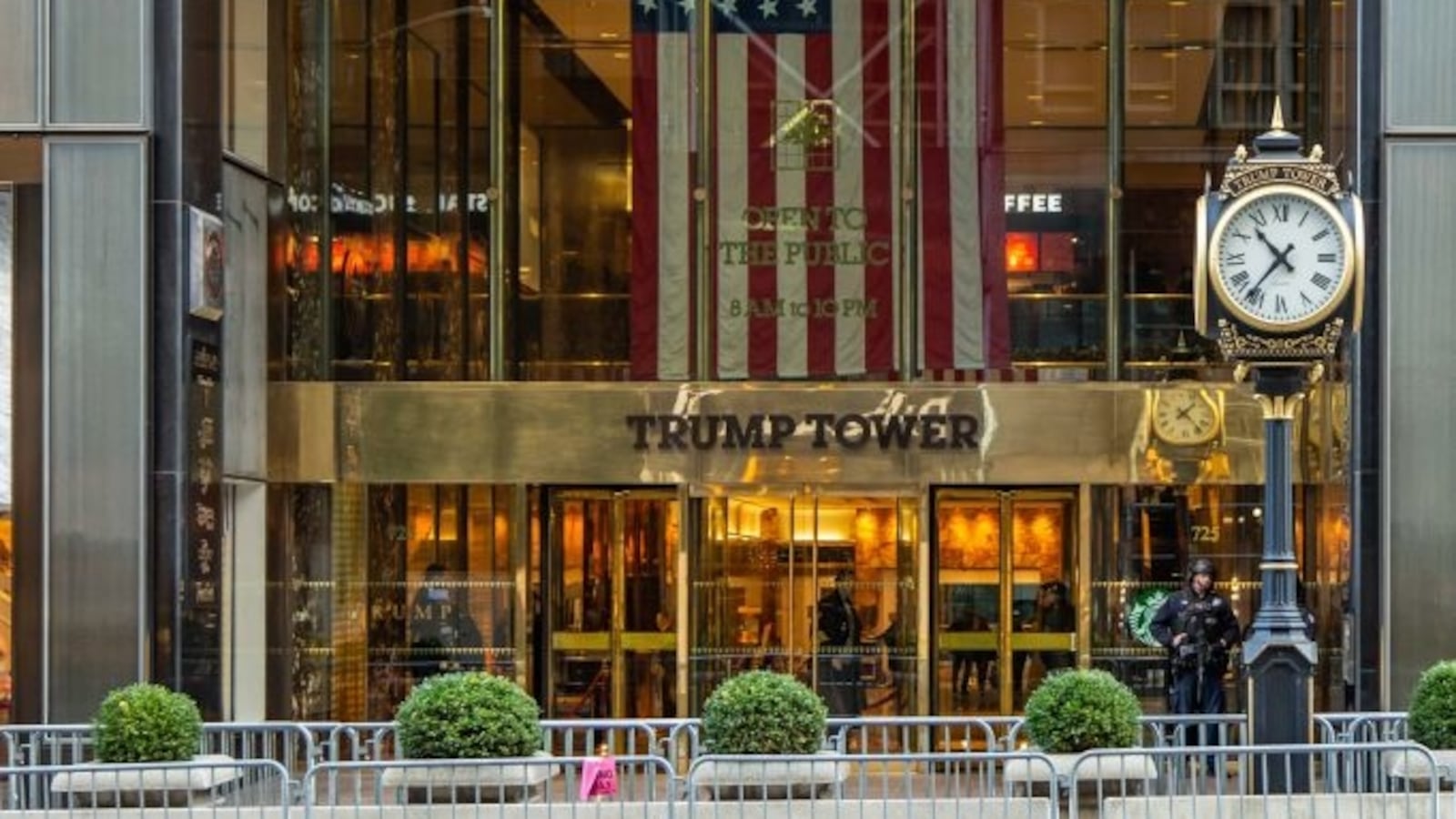 The clock by the main entrance of Trump Tower in New York City with the inscription on it and a U.S. flag.