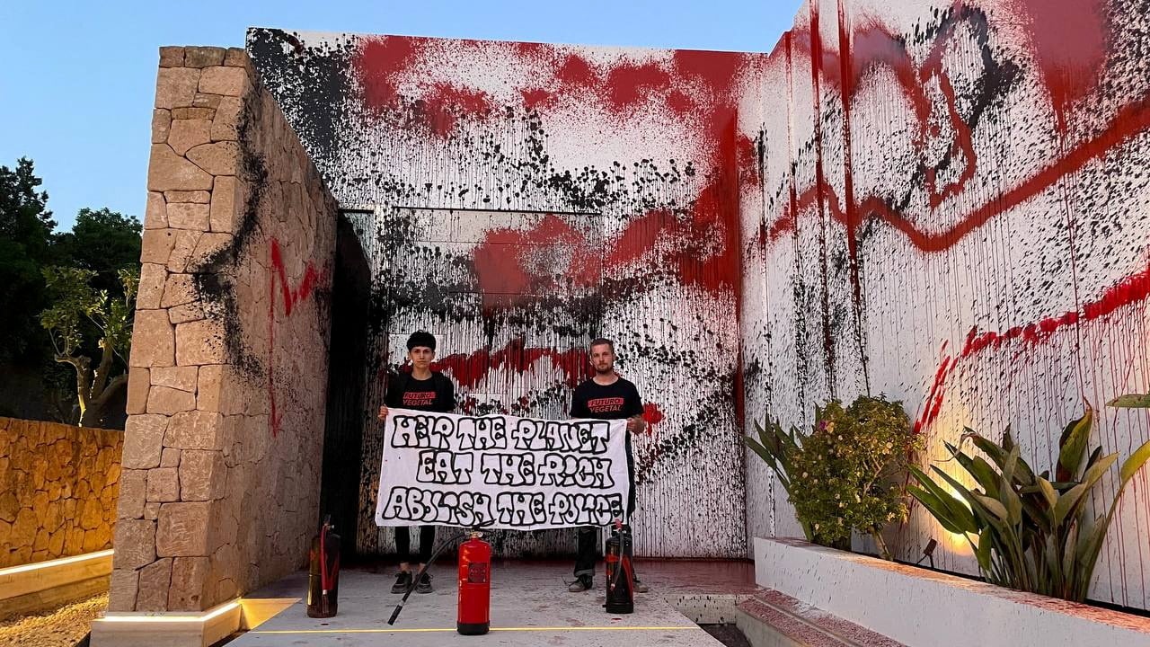 Two climate activists standing in front of Lionel Messi's house after vandalizing it.