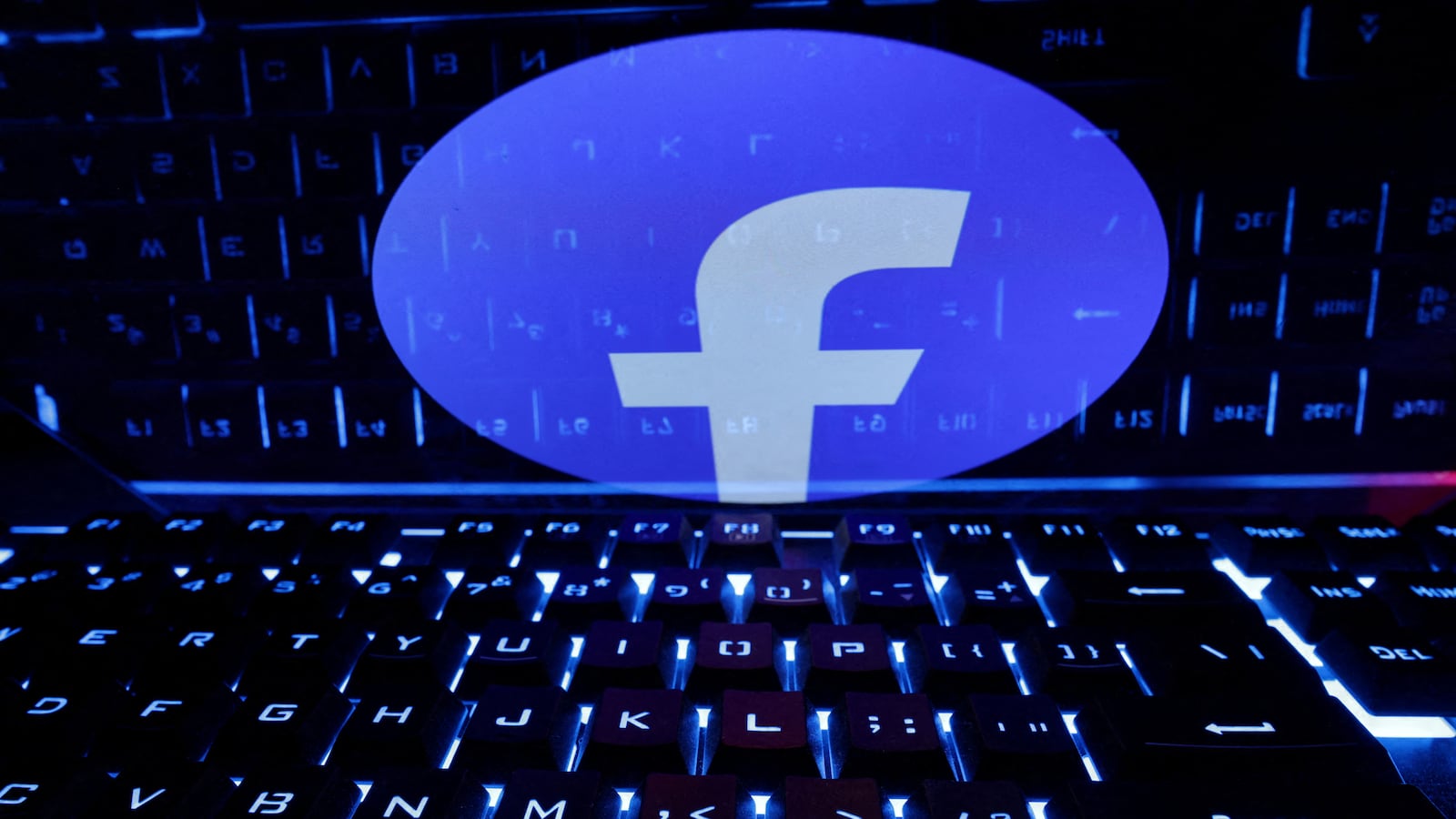 A keyboard is placed in front of a displayed Facebook logo