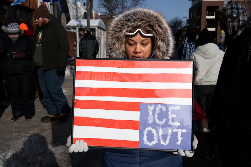 TOPSHOT - A woman holds a placard with an upside down American flag as mourners gather at a makeshift memorial in the area where Alex Pretti was shot dead a day earlier by federal immigration agents in Minneapolis, Minnesota, on January 25, 2026. On January 24, federal agents shot dead US citizen Alex Pretti, a 37-year-old ICU nurse, while scuffling with him on an icy roadway, less than three weeks after an immigration officer shot and killed Renee Good, also 37, in her car.
His killing sparked new protests and impassioned demands by local leaders for the Trump administration to end its operation in the city. (Photo by ROBERTO SCHMIDT / AFP via Getty Images)