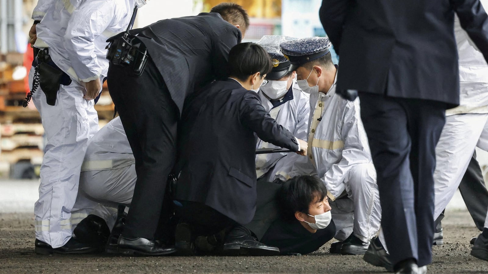 A man, believed to be a suspect who threw a pipe-like object near Japanese Prime Minister Fumio Kishida during his outdoor speech, is held by police officers