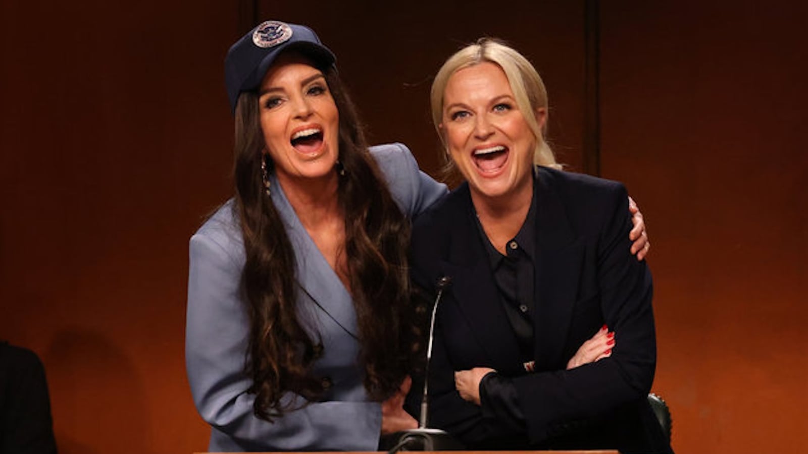 SATURDAY NIGHT LIVE -- Episode 1886 -- Pictured: (l-r) Special guest Tina Fey as Kristi Noem and Host Amy Poehler as Pam Bondi during the “Bondi Hearing” Cold Open on Saturday, October 11, 2025 -- (Photo by: Will Heath/NBC)
