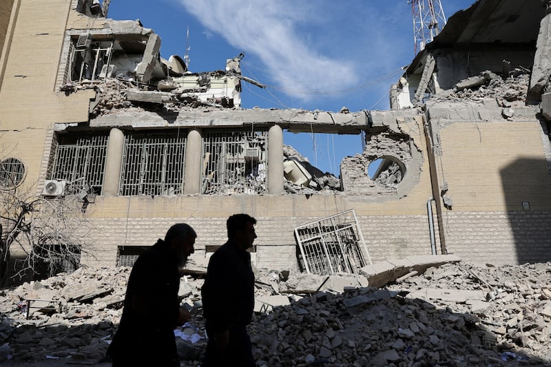 People walk past damaged buildings following a strike on a police station, amid the U.S.-Israeli conflict with Iran, in Tehran, Iran, March 4, 2026.
