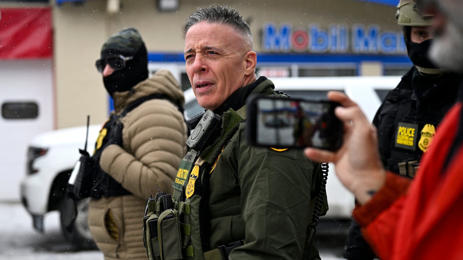 MINNEAPOLIS, MINNESOTA - JANUARY 21: A community member records U.S. Border Patrol Commander Gregory Bovino (C) as federal agents stop at a gas station on January 21, 2026 in Minneapolis, Minnesota. A reported 3,000 Department of Homeland Security federal agents have been deployed to the state, with more on the way, amid the Trump administration's major crackdown on immigration enforcement. (Photo by Stephen Maturen/Getty Images)
