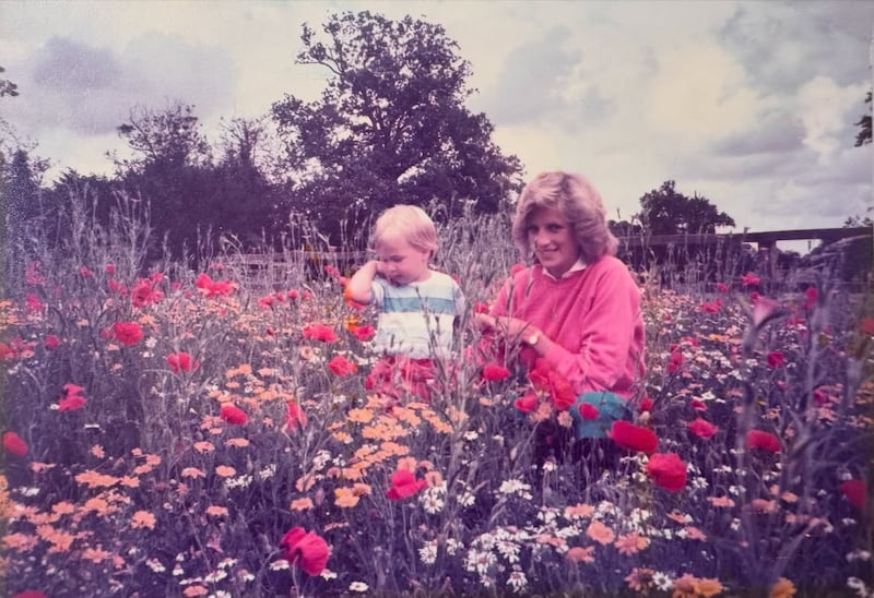 Princess Diana with Prince William, 2, in a field of flowers.