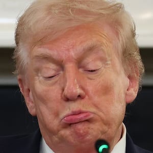 President Donald Trump reads a note during a roundtable discussion in the State Dining Room of the White House on October 08, 2025 in Washington, DC.