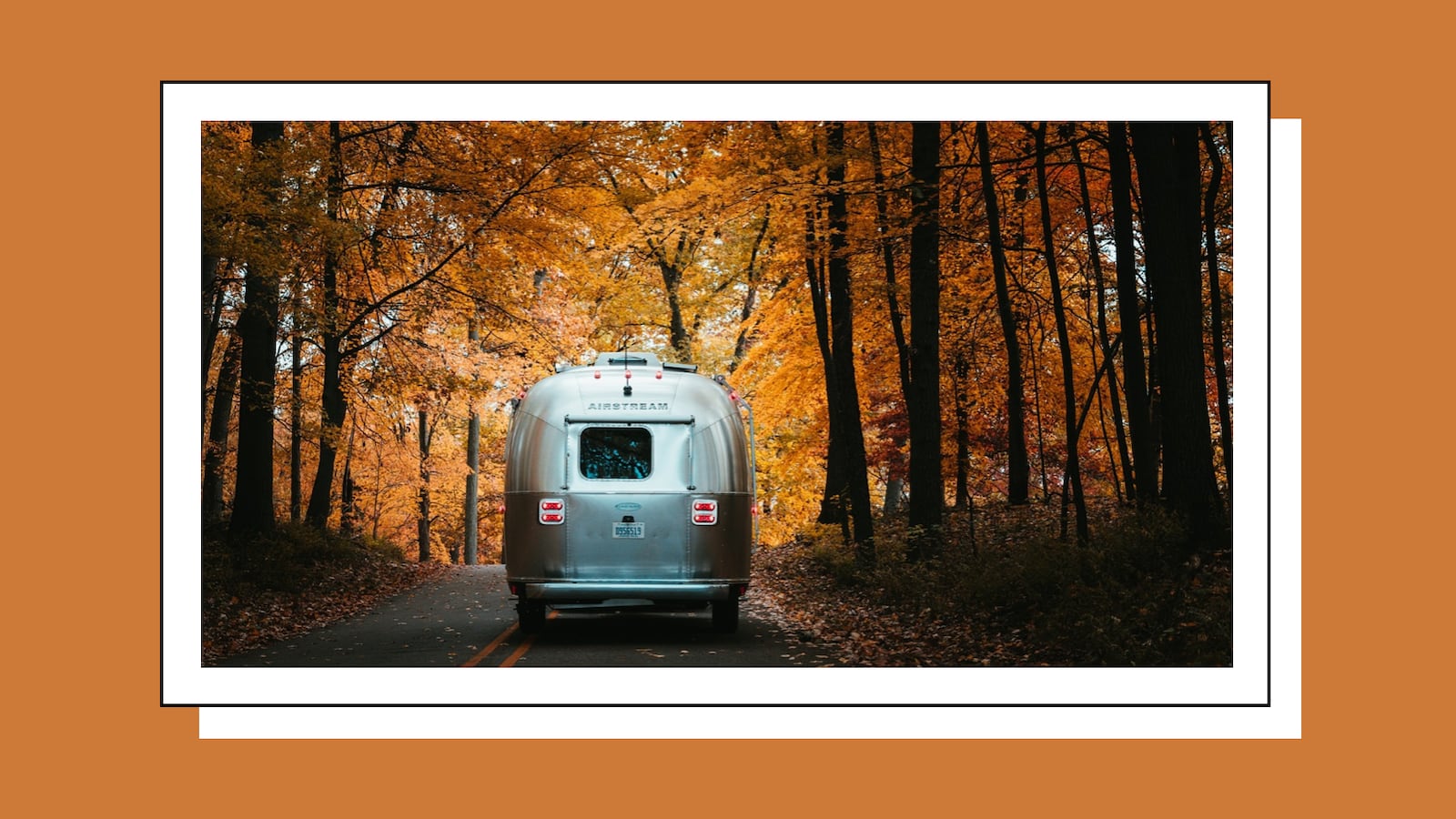 RV driving on a road during the fall.