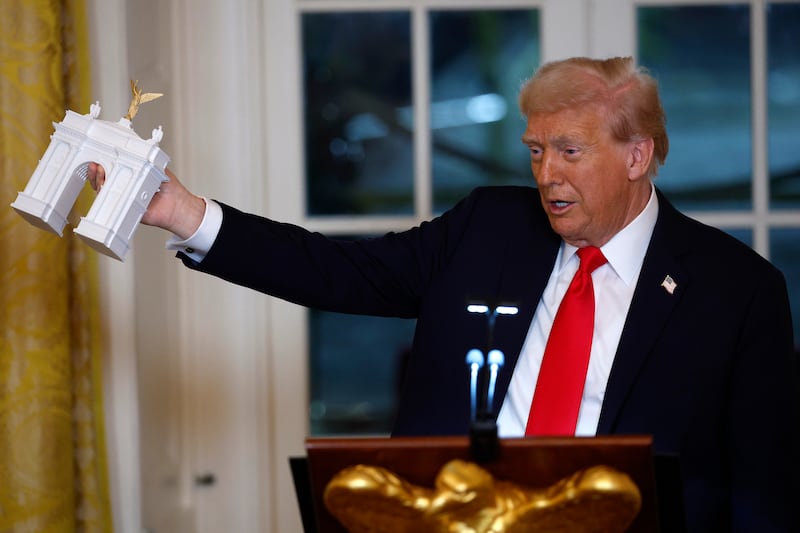 Trump holds a model of an arch