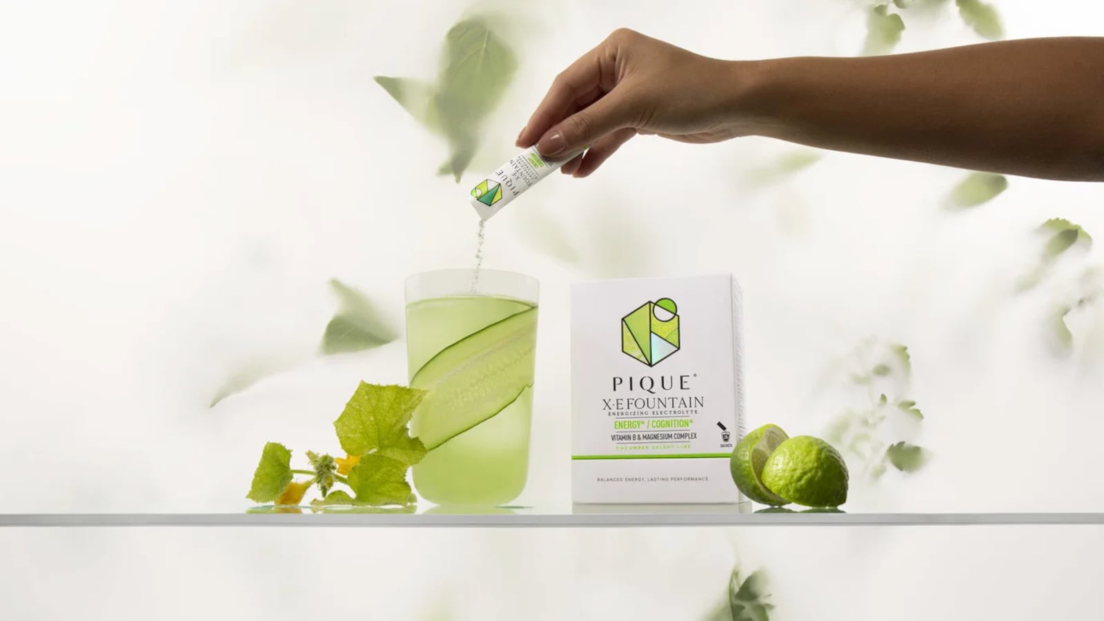 Hand dropping a packet of Pique Life's X·E Fountain energy drink into water