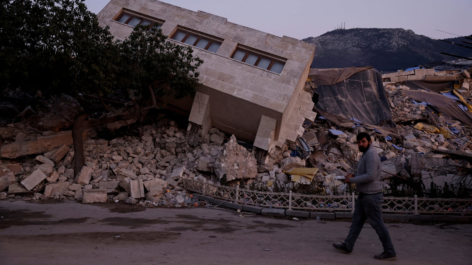 A man walks by a collapsed building and rubble, in the aftermath of a deadly earthquake, in Antakya, Hatay province, Turkey, Feb. 21, 2023.