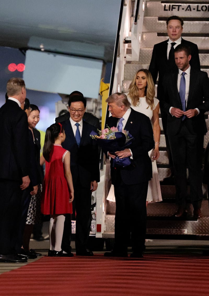 U.S. President Donald Trump receives flowers, next to Chinese Vice President Han Zheng, Elon Musk, Eric Trump and his wife Lara, during an arrival ceremony at Beijing Capital International Airport, in Beijing, China, May 13, 2026. REUTERS/Evan Vucci