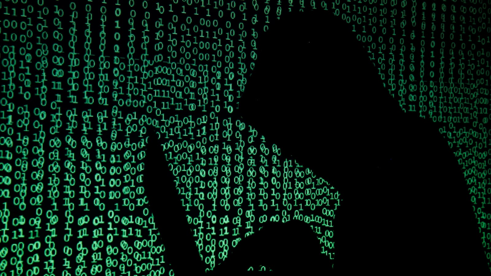 A hooded man holds a laptop computer as cyber code is projected on him in this illustration picture taken on May 13, 2017.