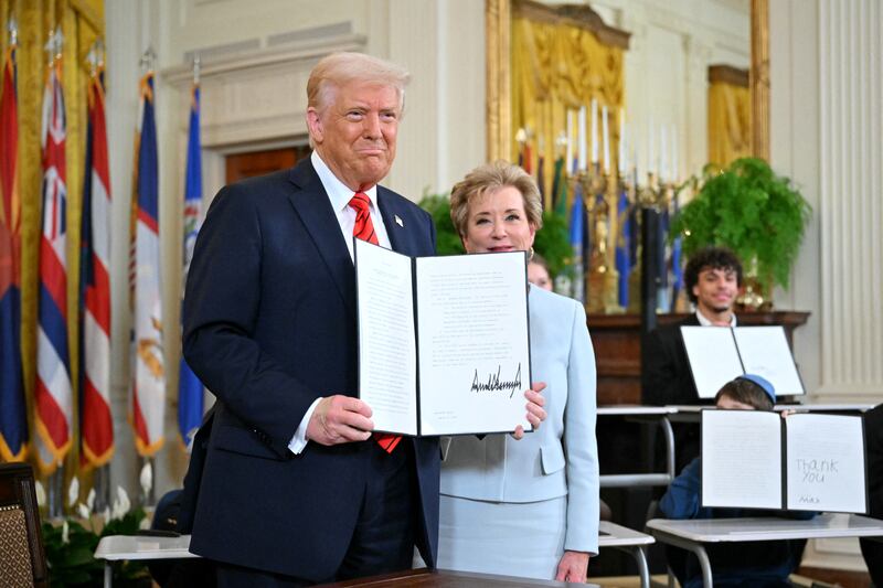 US President Donald Trump holds an executive order after signing it alongside US Secretary of Education Linda McMahon (R) in the East Room of the White house in Washington, DC,