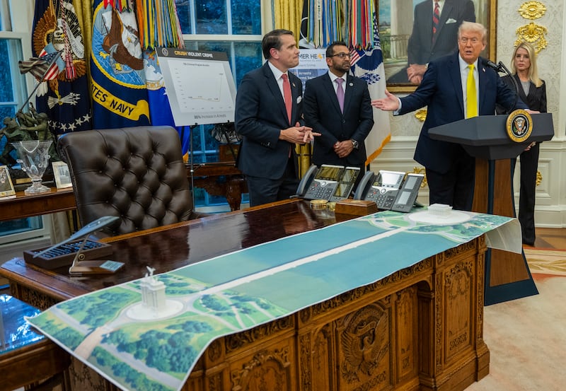 US President Donald Trump speaks accompanied by (L-R) Deputy Attorney General Todd Blanche, FBI Director Kash Patel and Attorney General Pam Bondi as a plan for an arch across from the Lincoln Memorial is seen on the Resolute Desk in the Oval Office of the White House, in Washington, DC, October 15, 2025.