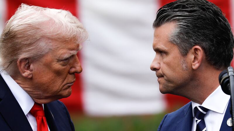 Hegseth looking at Trump behind an American flag