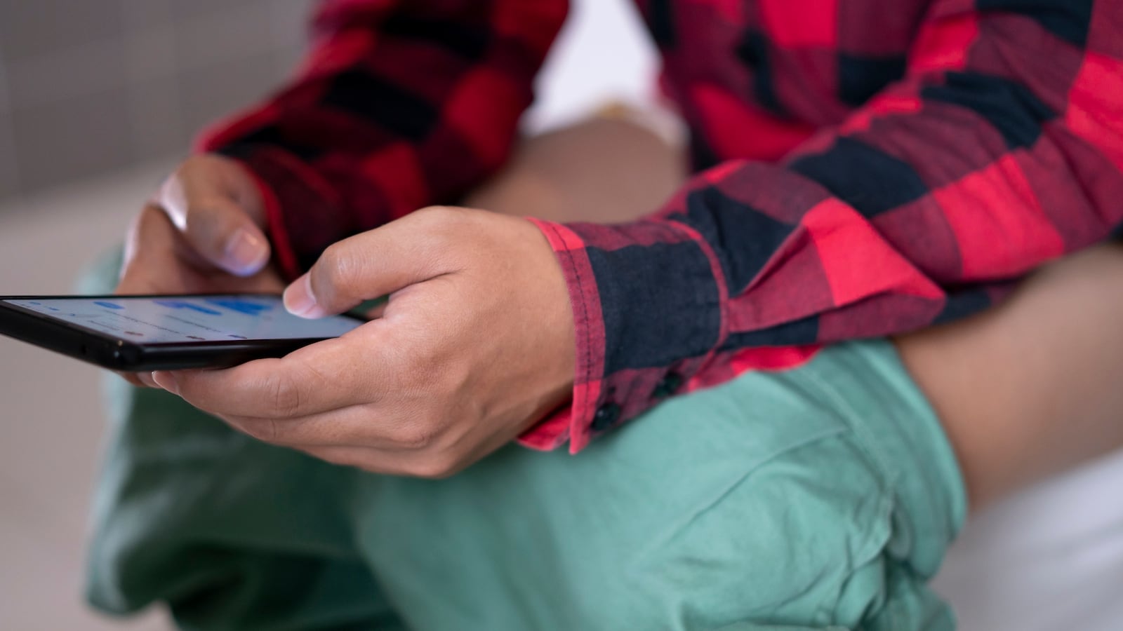 Man using a smart phone while sitting on the toilet