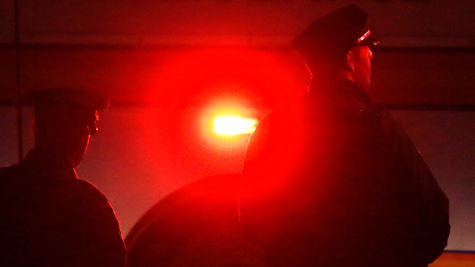 Police watch an ambulance as it leaves a crime scene.