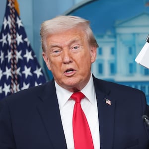 President Donald Trump displays a stack of papers labeled "The White House Accomplishments" as he arrives for a press briefing on January 20, 2026.