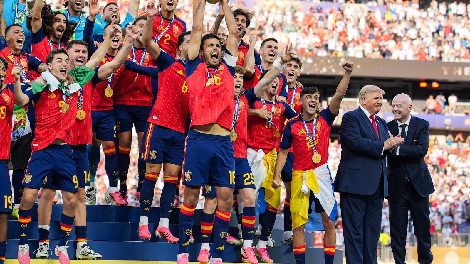 EAST RUTHERFORD, NEW JERSEY - JULY 19: US President Donald Trump and FIFA President Gianni Infantino stand on stage as Rodri #9 of Spain raises the FIFA World Cup Winner’s Trophy with his teammates after they defeated Argentina in the FIFA World Cup 2026 Final at New York New Jersey Stadium on July 19, 2026 in East Rutherford, New Jersey. Spain defeated reigning World Cup champions Argentina, who were led by Lionel Messi, with the lone goal coming from Ferran Torres #7 in the 106th minute of extra time. (Photo by Andrew Harnik/Getty Images)
