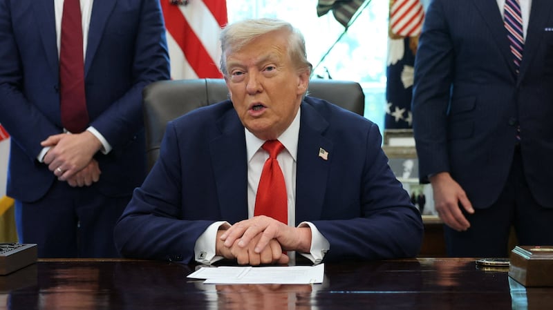 President Donald Trump keeps his right hand covered with his left while speaking  in the Oval Office on August 25, 2025, amid questions about his repeated bruising.