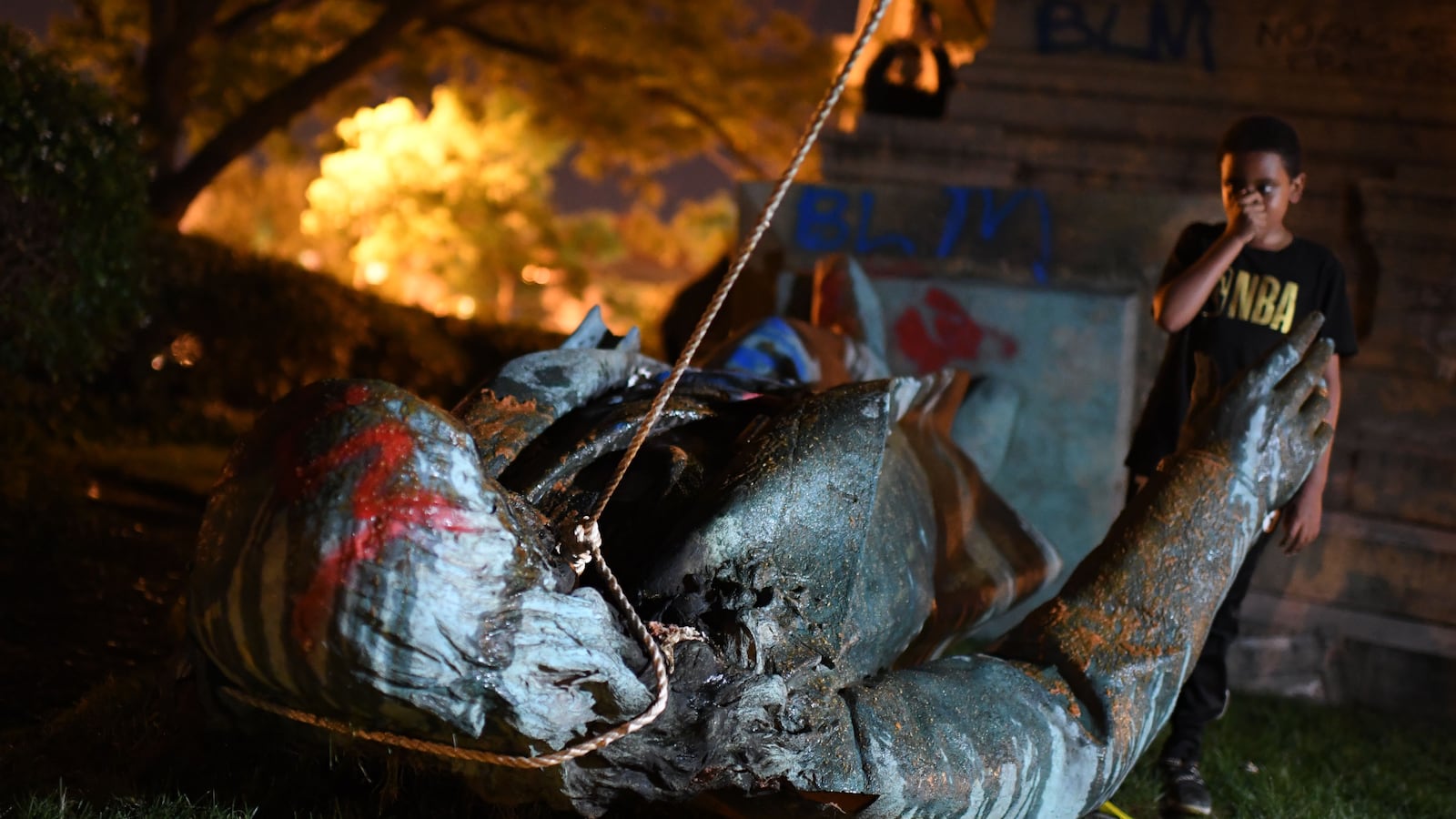 A young boy stands near the statue of Confederate general Albert Pike after it was toppled by protesters at Judiciary Square in Washington, DC on late June 19, 2020. -
