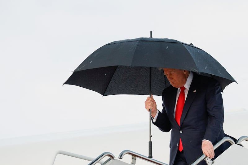 U.S. President Donald Trump holds an umbrella as he disembarks Air Force One upon arrival at Joint Base Andrews, after travelling to Milford, Michigan, in Maryland, U.S., July 27, 2026. REUTERS/Evan Vucci