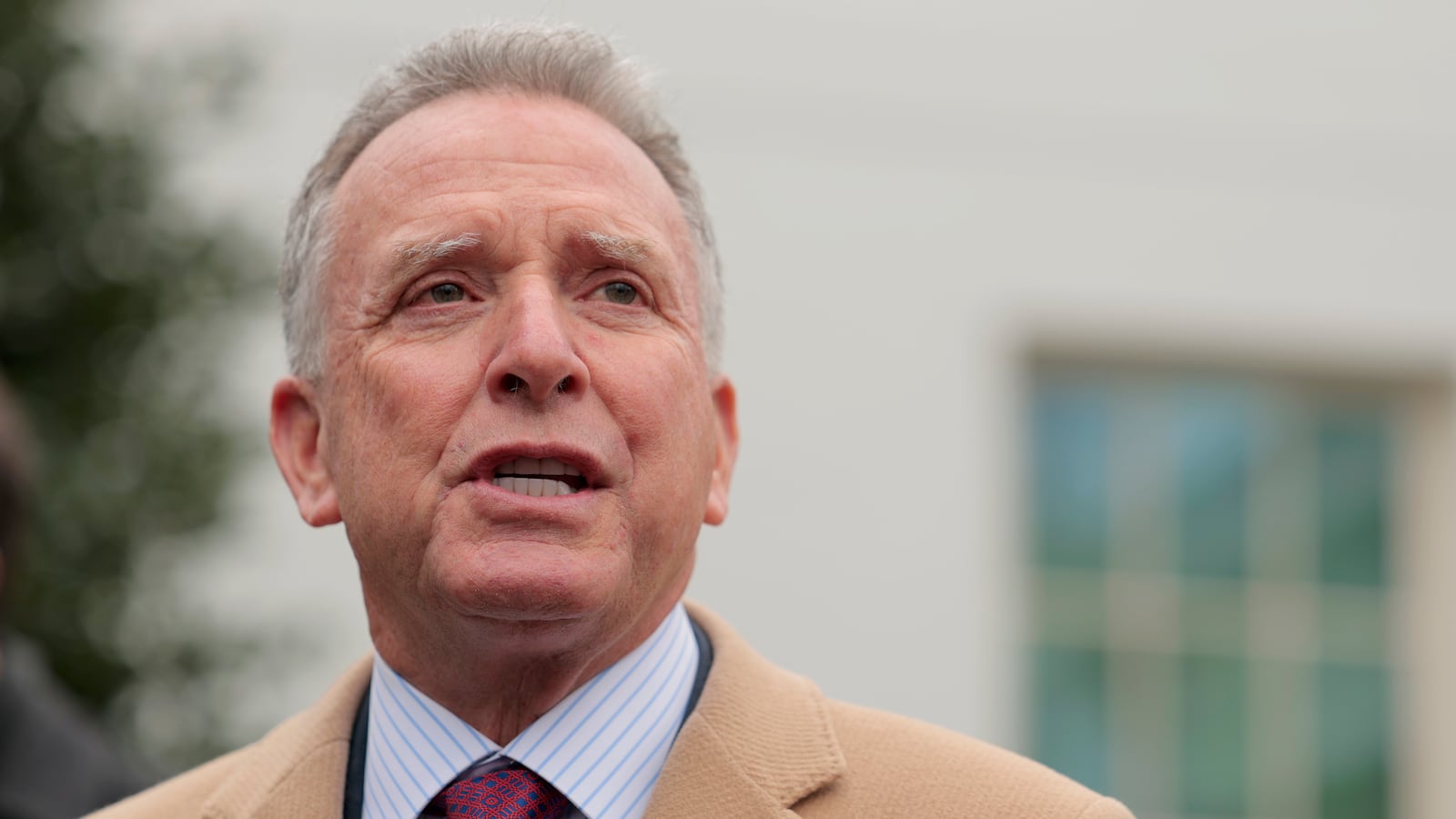 Wearing a striped shirt, blue and red tie, and tan overcoat, Steve Witkoff, special envoy to the Middle East, speaks to the press outside of the White House in March.