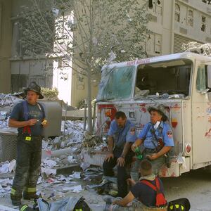 New York City firefighters take a rest at the World Trade Center after two hijacked planes crashed into the Twin Towers September 11, 2001 in New York.