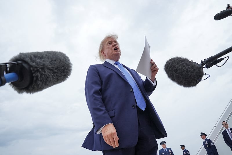U.S. President Donald Trump holds a printed-out article as he speaks to the members of the media after disembarking Marine One, before boarding Air Force One, en route to John F. Kennedy International Airport, at Joint Base Andrews, Maryland, U.S., August 14, 2026. REUTERS/Ken Cedeno