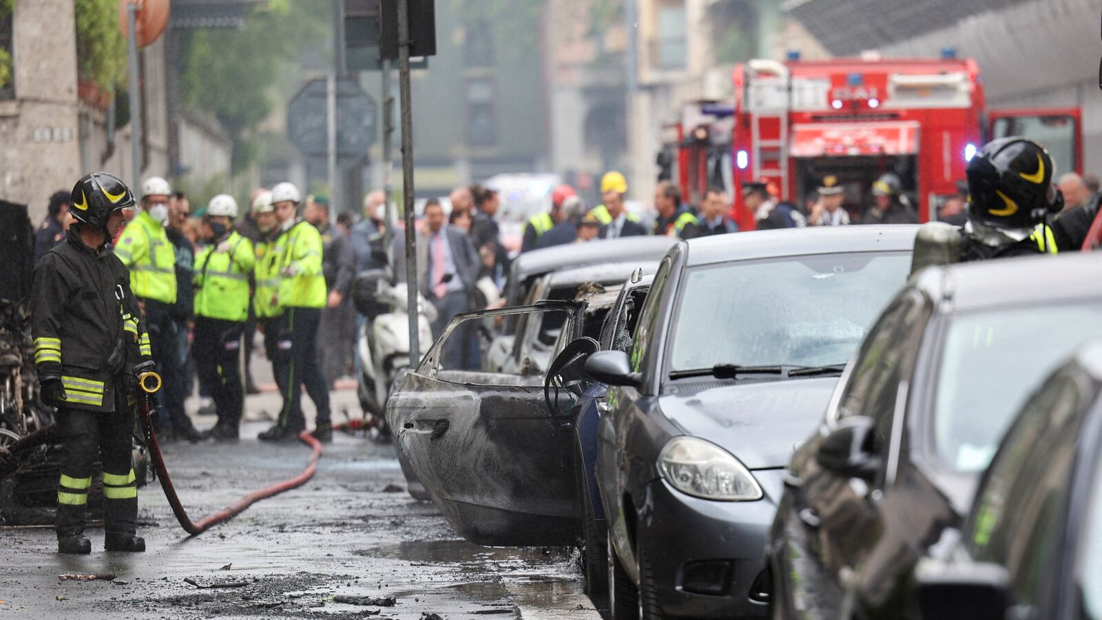 A firefighter stands next to a burnt vehicle following an explosion in the centre of Milan, Italy, May 11, 2023.