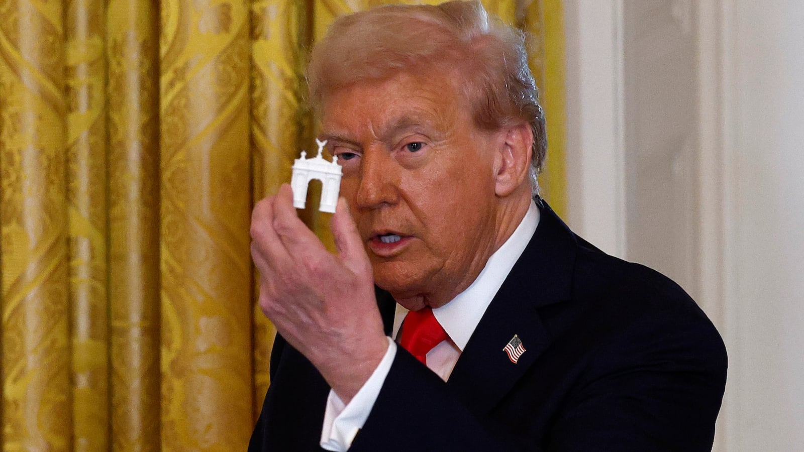 President Donald Trump holds models of an arch as he delivers remarks during a ballroom fundraising dinner in the East Room of the White House on October 15, 2025 in Washington, DC.