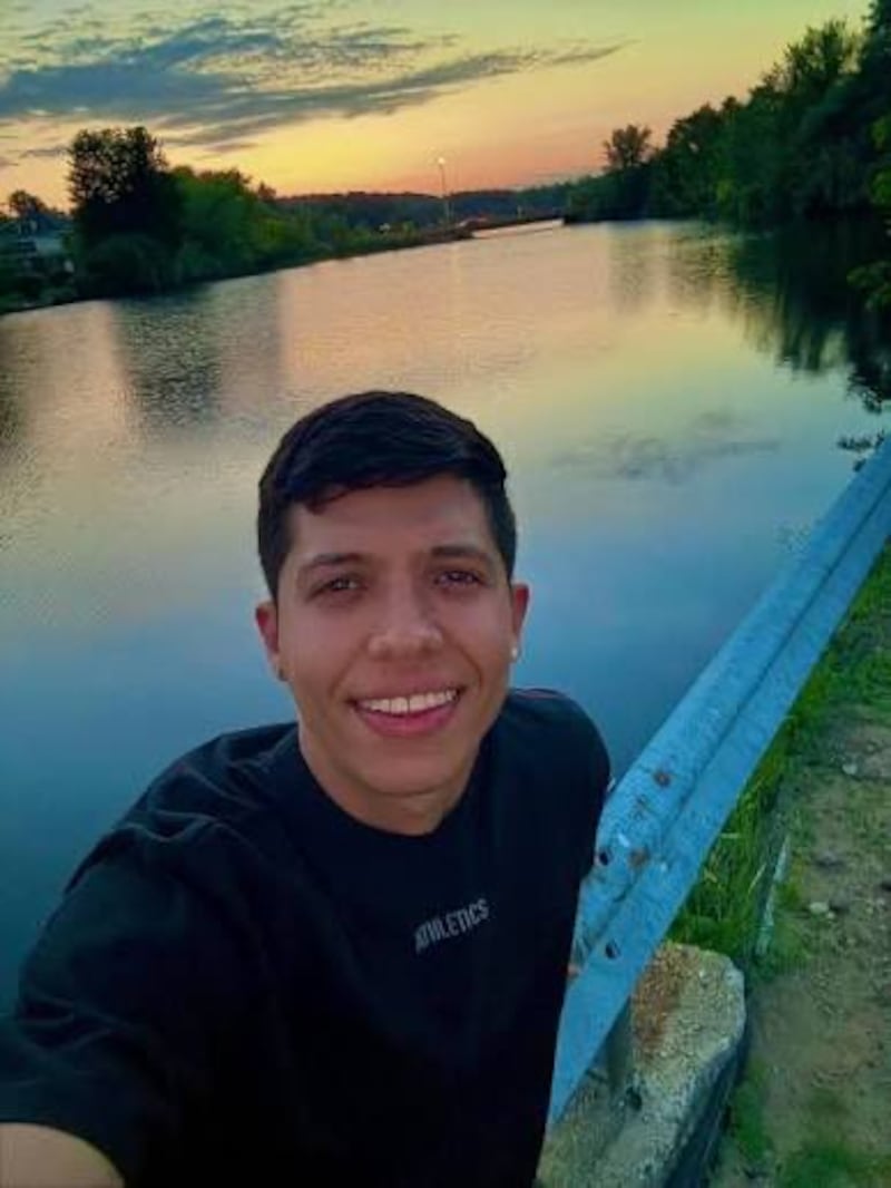 A man in front of a river with sunset behind
