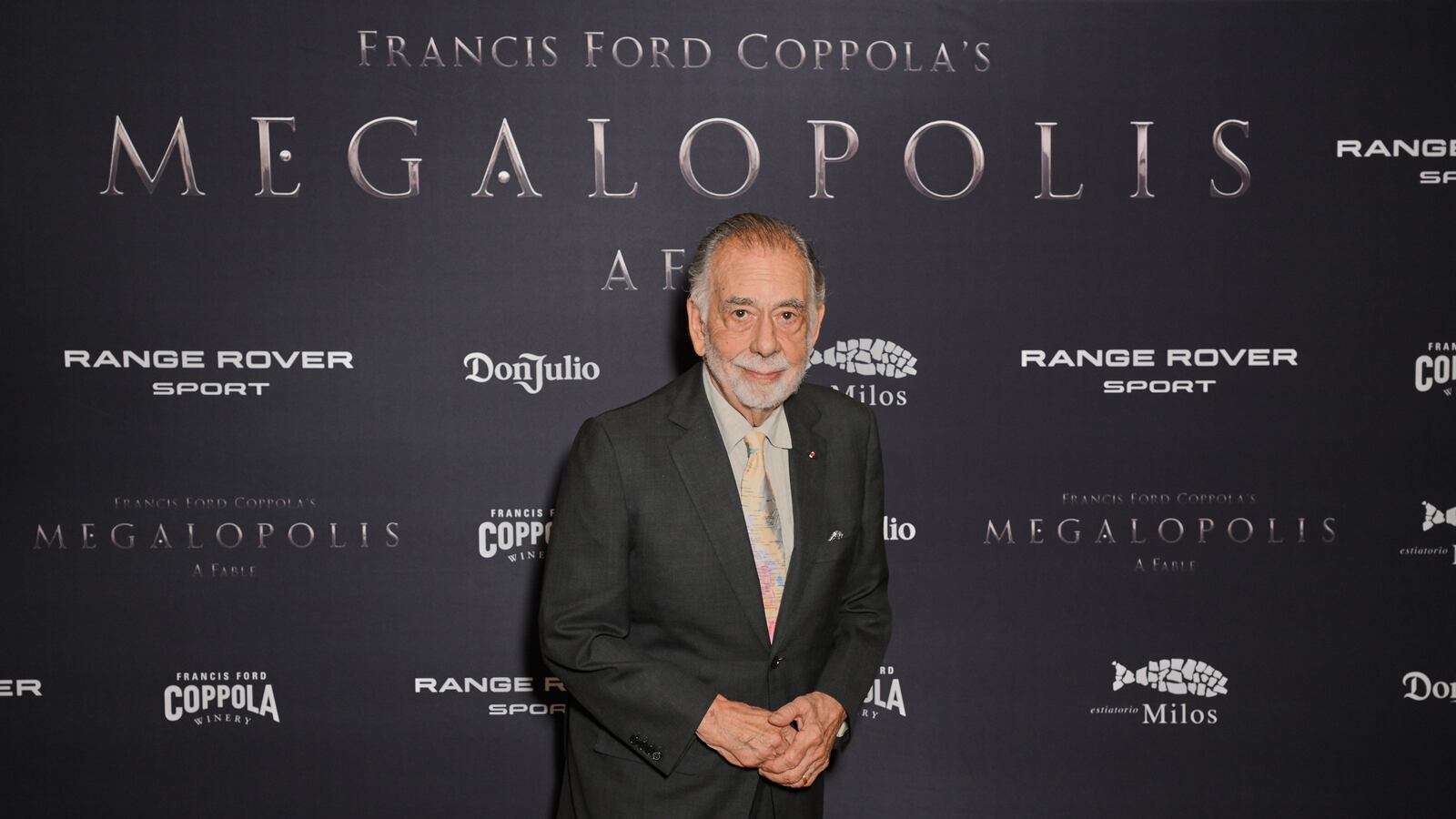 Francis Ford Coppola stands in front of a promotional background at the premiere of his film “Megalopolis”.