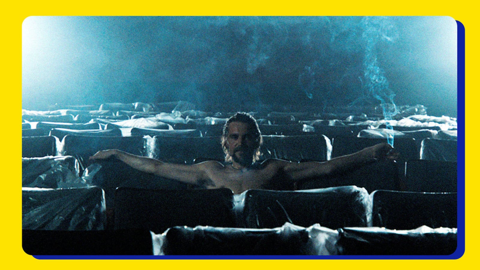 A man sits in a smokey theater.