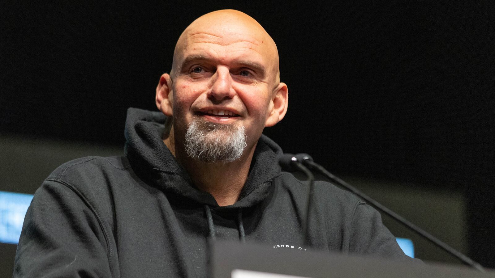 John Fetterman smiles at a podium