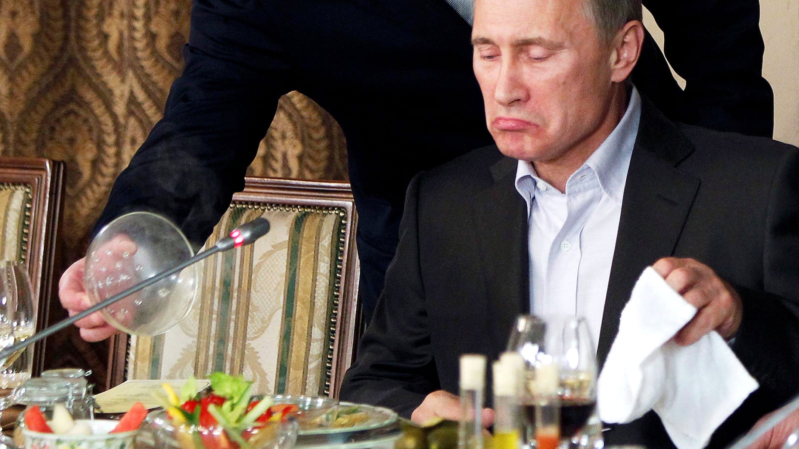 FILE PHOTO: Evgeny Prigozhin (L) assists Russian Prime Minister Vladimir Putin during a dinner with foreign scholars and journalists at the restaurant Cheval Blanc on the premises of an equestrian complex outside Moscow November 11, 2011. Picture taken November 11. REUTERS/Misha Japaridze/Pool/File Photo