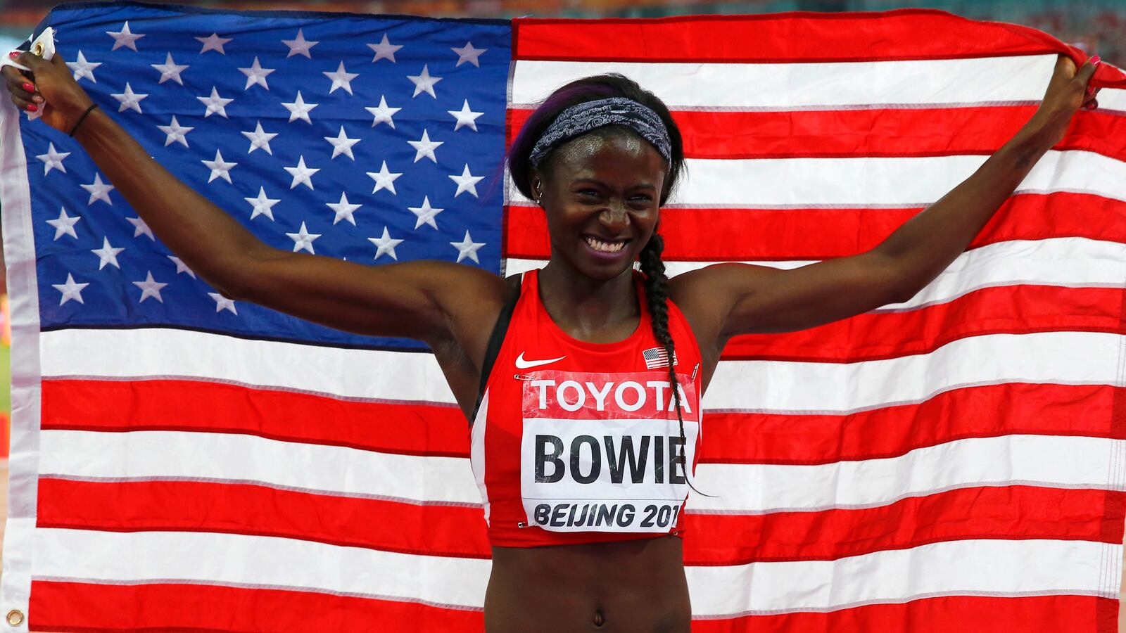 Third placed Tori Bowie of the U.S. celebrates with a national flag after competing the women's 100 metres final during the 15th IAAF World Championships at the National Stadium in Beijing, China, August 24, 2015.