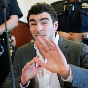 NEW YORK, NEW YORK - DECEMBER 16: Luigi Mangione talks to a photographer as he appears for a suppression of evidence hearing in the killing of UnitedHealthcare CEO Brian Thompson in Manhattan Criminal Court on December 16, 2025 in New York City. Mangione's lawyers will argue to have the evidence thrown out because police officers allegedly did not read Mangione his Miranda rights and did not have a proper warrant when they searched his backpack at a Pennsylvania McDonald's last December. He is accused of fatally shooting UnitedHealthcare CEO Brian Thompson and faces state and federal murder charges. (Photo by Seth Wenig-Pool/Getty Images)