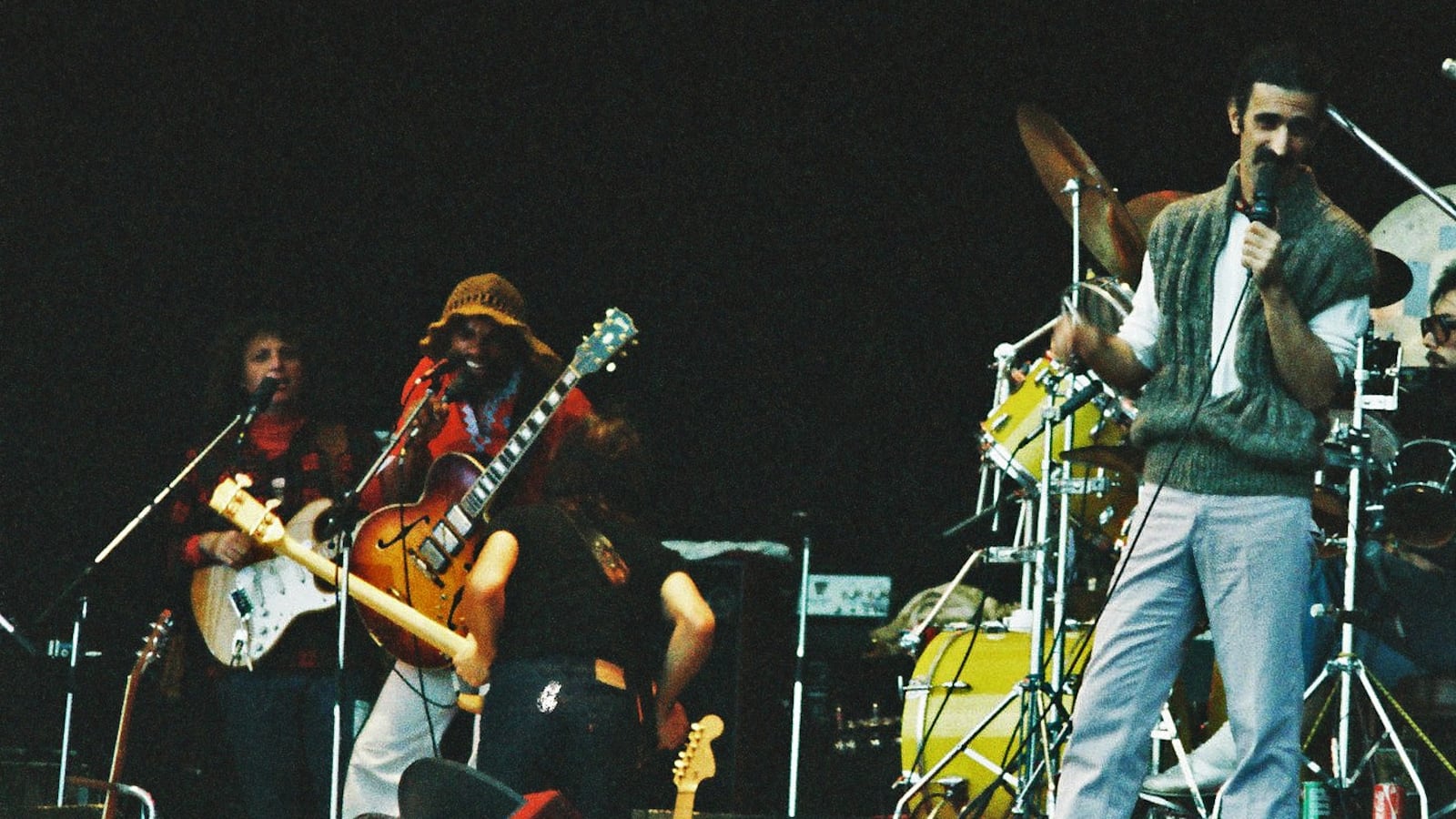 KNEBWORTH, UNITED KINGDOM - SEPTEMBER 9: Frank Zappa performs on stage with band members (L-R) Denny Walley, Ike Willis, Arthur Barrow (back to camera) and drummer Vinnie Colaiuta at The Knebworth Festival on September 9th, 1978 in Knebworth, United Kingdom. (Photo by Pete Still/Redferns)