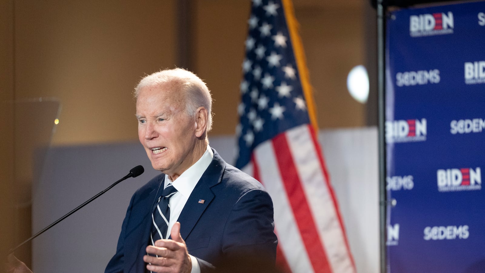 Former President Joe Biden speaks at a podium in front of the U.S. flag