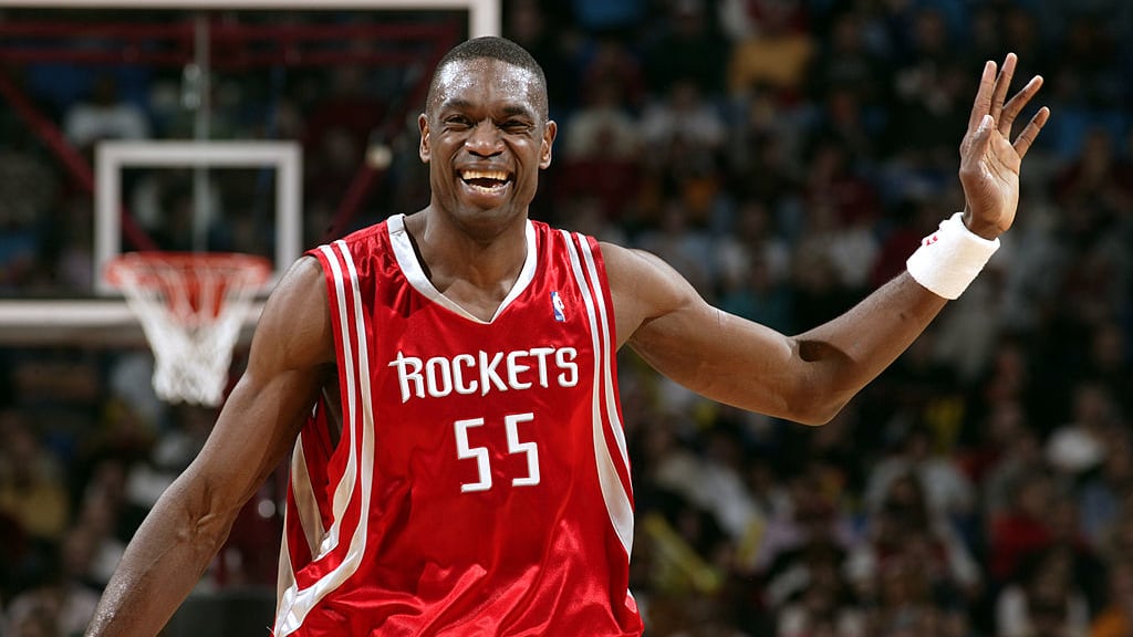 Dikembo Mutombo smiles on court while playing for the Houston Rockets.