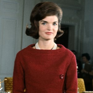 American First Lady Jacqueline Kennedy (1929 - 1994), in a red dress, stands in before a dining room table in the White House during the filming of a CBS News Special program called 'A Tour of the White House with Mrs. John F. Kennedy,' Washington DC, January 15, 1962. (Photo by CBS Photo Archive/Getty Images)