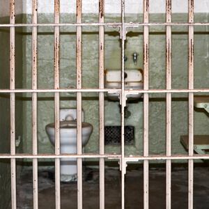 A picture of a jail cell, as seen through the bars.
