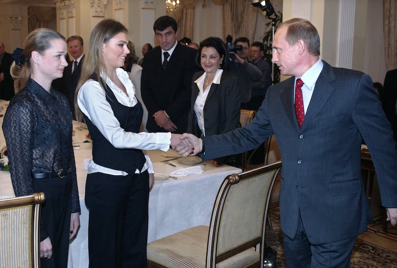 Russian President Vladimir Putin (R) shakes hands with famous Russian gymnasts Alina Kabayeva (C) and Svetlana Khorkina (L) during the meeting with sportsmen, candidates to Russian Olympic team for Olympics 2004, in the presidential residence in Novo-Ogaryovo outside Moscow, 10 March 2004. Vladimir Putin said Russian business is ready to support Russian sportsmen. AFP PHOTO / POOL (Photo by SERGEI CHIRIKOV / POOL / AFP) (Photo by SERGEI CHIRIKOV/POOL/AFP via Getty Images)