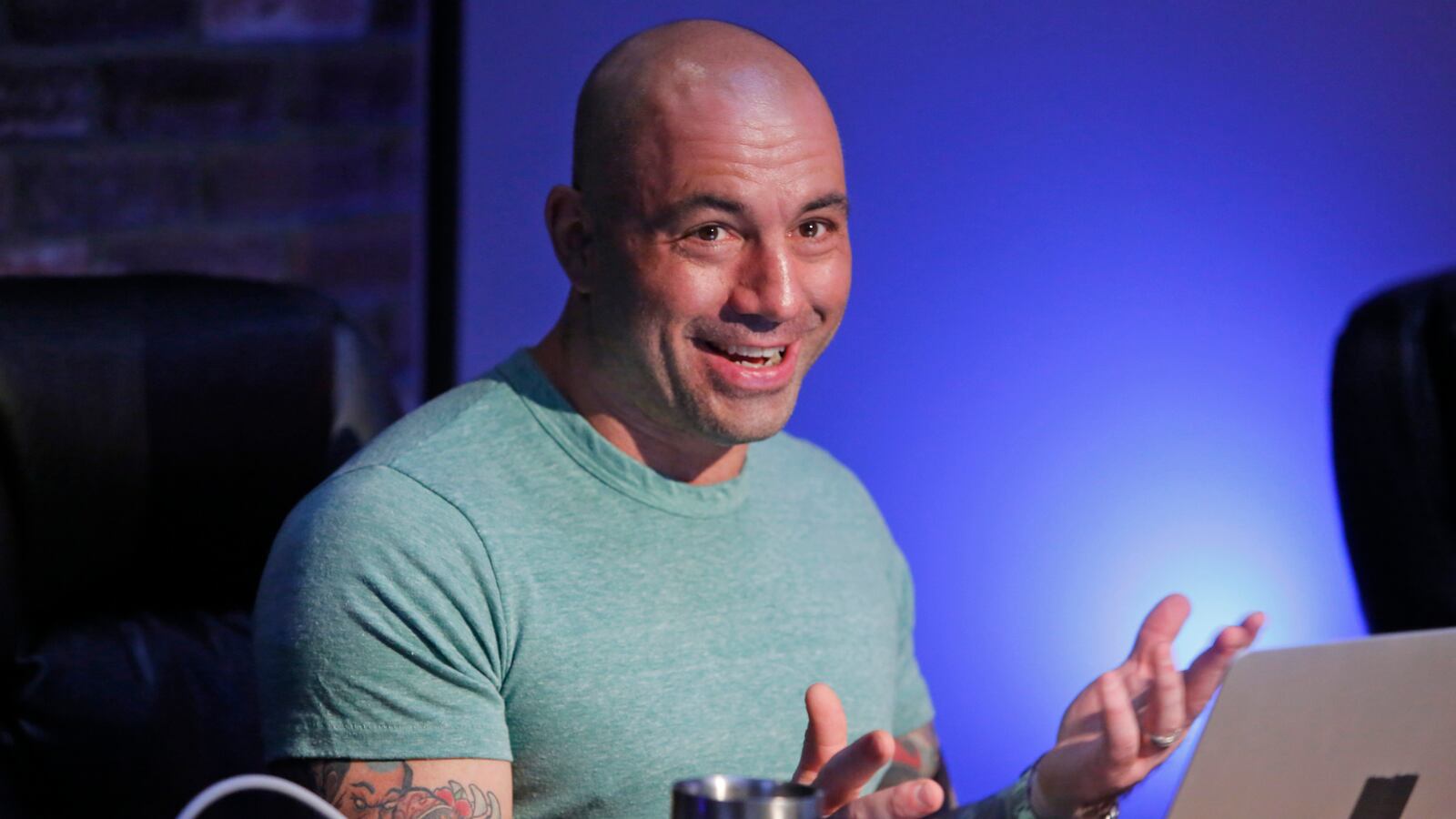 Joe Rogan is shown seated in his podcast studio.
