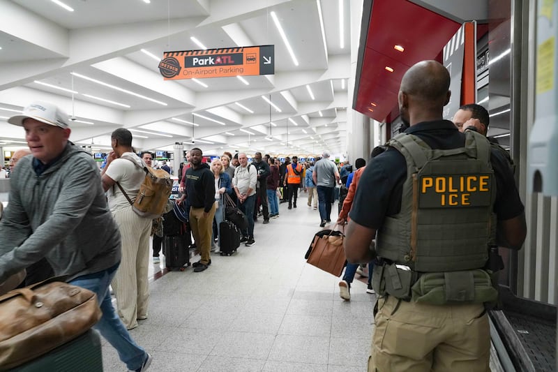 Ice agents look on as travelers stand in long lines at Atlanta Hartsfield-Jackson International Airport